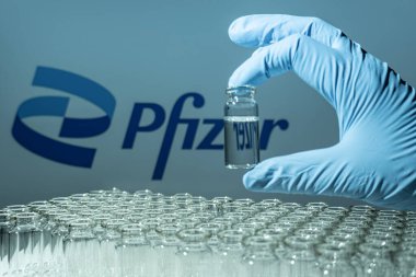 Toronto, Ontario, Kanada - 14 Şubat 2021: Pfizer ismi bulanık. Aşı uzmanı cam şişeyi Amerikan aşısıyla tutuyor. Coronavirus 'a karşı araştırma, COVID-19. Klinik değerlendirme.