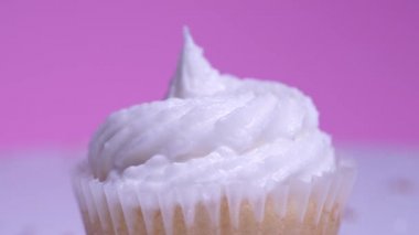 Cupcake makro yüzeysel alan görüşü derinliği. Süslü şekerli, fincanlı kek ve pembe arka planda beyaz vanilyalı krema. Lezzetli tatlılar kız doğum günü veya sevgililer günü için..
