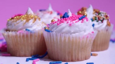 Cupcakes makro yüzeysel alan görüşü derinliği. Süslü şekerli fincanlar, pembe arka planda beyaz vanilya kremalı kekler. Lezzetli çörekler kız doğum günü veya sevgililer günü için..
