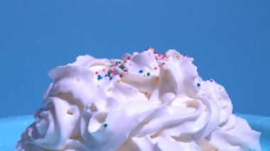 Ev yapımı çırpılmış kremaya bir kase tatlı serpiyorum. Tatlı kremanın üzerine renkli krema dökülüyor, mavi arkaplan, pasta ve fırın için süsleme, donda çikolata.