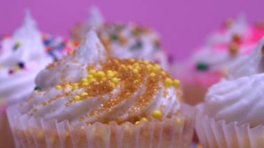 Tatil rotasyonu için renkli kekler, sığ alan derinliği. Buzlu keklere odaklanmak için makroyu kapat. Pembe arka plan. Yıl dönümünde ya da doğum gününde lezzetli tatlıların sunumu.