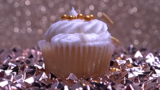 かわいいカップケーキマクロ視野の浅い深さ 砂糖のスプリンクルで装飾 金地に白いバニラクリームをかけたカップケーキ 誕生日やバレンタインのためのおいしいデザートマフィンを作る — ストック動画