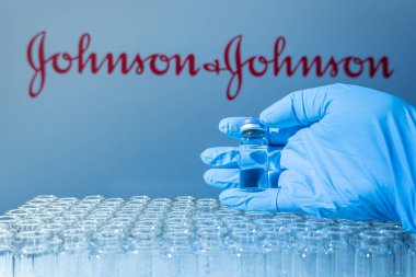 Toronto, Ontario, Kanada - 14 Şubat 2021: Johnson ve Johnson isimleri bulanık. Cam şişeyi Amerikan aşısıyla tutan bilim adamı. Coronavirus 'a karşı araştırma, COVID-19. Klinik değerlendirme.