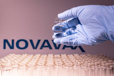 Toronto, Ontario, Kanada - 14 Şubat 2021 Novavax ismi bulanık. Aşı uzmanı cam şişeyi Amerikan aşısıyla tutuyor. Coronavirus 'a karşı araştırma, COVID-19. Klinik değerlendirme.