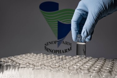 Toronto, Ontario, Kanada - 14 Şubat 2021 Sinopharm ismi bulanık. Cam şişeyi Çin aşısıyla tutan aşı bilimcisi. Coronavirus 'a karşı araştırma, COVID-19. Klinik değerlendirme.