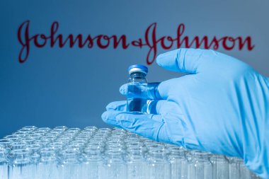 Toronto, Ontario, Kanada - 14 Şubat 2021: Johnson ve Johnson isimleri bulanık. Cam şişeyi Amerikan aşısıyla tutan bilim adamı. Coronavirus 'a karşı araştırma, COVID-19. Klinik değerlendirme.