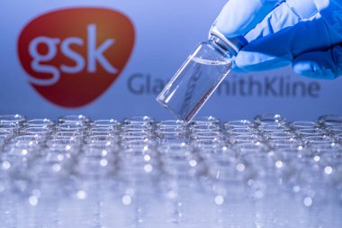 Toronto, Ontario, Kanada - 14 Şubat 2021: GSK GlaxoSmithKline ismi bulanık. Aşı bilimcisi cam şişeyi İngiltere aşısıyla tutuyor. Coronavirus 'a karşı araştırma, COVID-19. Klinik değerlendirme.