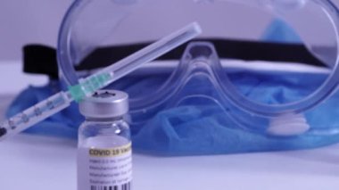 COVID-19 aşısı ve şırınga hareket ediyor. Coronavirus aşısı olan ampuller ve şişeler doktor masasında hazır. Tıp uzmanları tarafından yapılan kas içi aşılama..