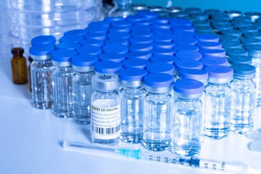 Bir araştırma laboratuarında Covid-19 Coronavirus aşısı içeren cam şişe ve şırınga. Tıp işçisi laboratuvar masasında tedavisi olan ampuller. Sars-cov-2 salgın konsepti. 