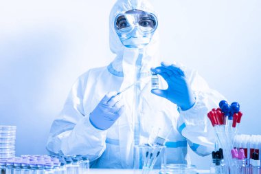 Tıbbi maske ve PPE 'deki doktor ya da hemşire Coronavirus aşısı şişesi ve şırınga taşıyor. COVID-19 tedavi yönetimi. Hastanede sağlık görevlileri tarafından hazırlanmış iğneyi kullanmaya hazır.. 