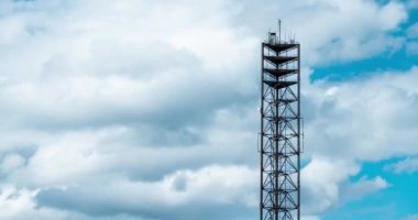 Cep telefonu iletişim antenleri, 3G, 4G, 5G, 6G. Yazın bulutlu mavi gökyüzünü hızla hareket ettiren antenin zaman akışı. Vericili hücresel GSM kulesi. Telekomünikasyon baz istasyonu ağı.