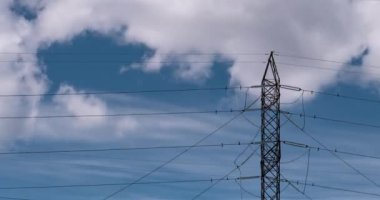 Yüksek voltajlı elektrik vericisi zaman aşımına uğradı. Mavi gökyüzü ve bulutlu sanayi aktarım güç hattı zaman ayarlı. 4K ham B-roll görüntüsü. Tozdan arınmış.