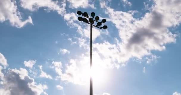 在夕阳和夏日的云彩映衬下 经过了足球场的光塔 电影般的快速而流畅的天空移动 足球场的手电筒和晚班时间 — 图库视频影像