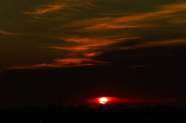 Günbatımı şehir manzarası. İnanılmaz kırmızı turuncu akşam bulutları ve Amerikan şehrinde güneş. Bulutlu yaz manzarası. Kuşlardan, böceklerden ve tozdan arınmış.