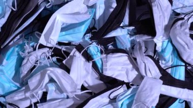 Masada tıbbi maskeler var. Kullanılmış kişisel koruyucu ekipman yığını PPE. Koronavirüs salgını sırasında cerrahi maskeler tarafından kirlilik. Bir sürü Covid-19 plastik atık ve çöp, tek kullanımlık maskeler..