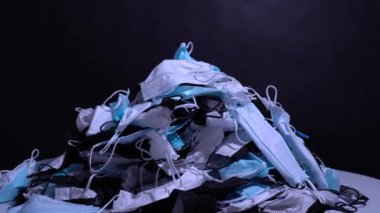 Masada tıbbi maskeler var. Kullanılmış kişisel koruyucu ekipman yığını PPE. Koronavirüs salgını sırasında cerrahi maskeler tarafından kirlilik. Bir sürü Covid-19 plastik atık ve çöp, tek kullanımlık maskeler..