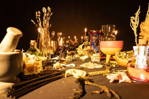 Occult and esoteric witch doctor still life. Selective focus. Halloween background with magic objects. Black candles skull, crystal stones, and potions vials on witch table. Mystic witchery with weeds