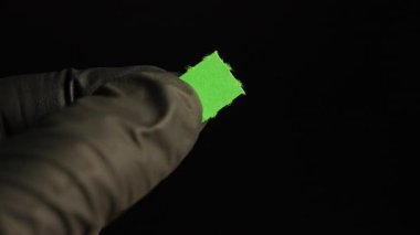 Tıbbi araştırmacılar ellerinde LSD şeritli siyah eldivenlerle Lysergic asit ilacının kuru damlasını tutuyorlar. Yakın plan çekim. Depresif hastalıkların tedavisinde ve deneylerinde kullanılan LSD