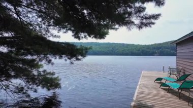 Yüzen rıhtımdan ya da tekne iskelesinden kulübe alanı manzarası. Yaz mevsimi köy manzarası orman ve göl suyuyla çevrili. Güneş banyosu sandalyeleri, Hastings Highlands, Bancroft, Ontario, Kanada.