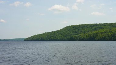 Kır evindeki göl suyunun üzerindeki orman manzarası güneşli bir yaz gününde vahşi doğada huzurlu bir manzara. Sakin göl mavi gökyüzü, sakin Hastings Highlands, Bancroft, Ontario, Kanada.