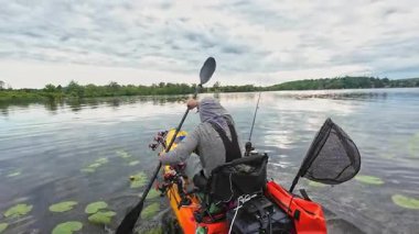 Balıkçılık sporu sırasında gölde ya da gölette kano küreği. Balıkçı, pedallı kano kürekleri ve oyuncu kadrosuyla. Boş zaman aktif yaşam tarzı eğlencesi ve spor aktivitesi.