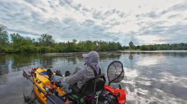 Balıkçılık sporu sırasında gölde ya da gölette kano küreği. Balıkçı, pedallı kano kürekleri ve oyuncu kadrosuyla. Boş zaman aktif yaşam tarzı eğlencesi ve spor aktivitesi.