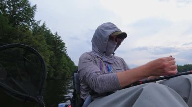 Angler oltaya gece sürüngeni yemi taktı. Bob tekniğiyle birlikte. Kano sporu balıkçılığı. Angler manzaralı sahil şeridinde kano balıkçılığını seviyor. Simcoe Gölü, Ontario, Kanada 'da huzurlu su batımı
