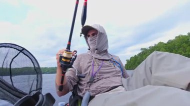 Angler oltaya gece sürüngeni yemi taktı. Bob tekniğiyle birlikte. Kano sporu balıkçılığı. Angler manzaralı sahil şeridinde kano balıkçılığını seviyor. Simcoe Gölü, Ontario, Kanada 'da huzurlu su batımı
