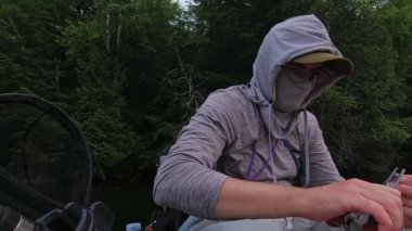 Balıkçı oltayı olta, olta ve olta iğnesiyle düzeltiyor. Kano sporu balıkçılığı. Angler manzaralı sahil şeridinde kano balıkçılığını seviyor. Simcoe Gölü, Ontario, Kanada 'da huzurlu su batımı