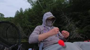 Balıkçı oltayı olta, olta ve olta iğnesiyle düzeltiyor. Kano sporu balıkçılığı. Angler manzaralı sahil şeridinde kano balıkçılığını seviyor. Simcoe Gölü, Ontario, Kanada 'da huzurlu su batımı