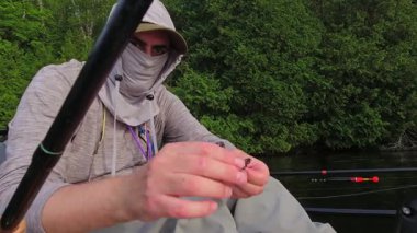 Balıkçı oltaya gece sürüngeni yemi taktı, balık tutma tekniğini bıraktı. Kano sporu balıkçılığı. Angler manzaralı sahil şeridinde kano balıkçılığını seviyor. Simcoe Gölü, Ontario, Kanada 'da huzurlu su batımı