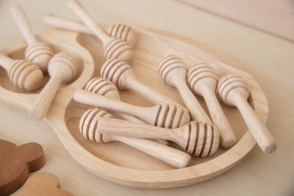 wooden honey stick in wooden tray