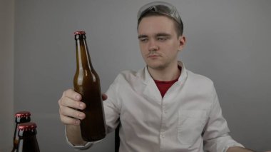 Genç bir bira üreticisi ürünleri hazırlar ve ekipmanların kalitesini ve evde demlenen ballı biranın kalitesini kontrol eder.