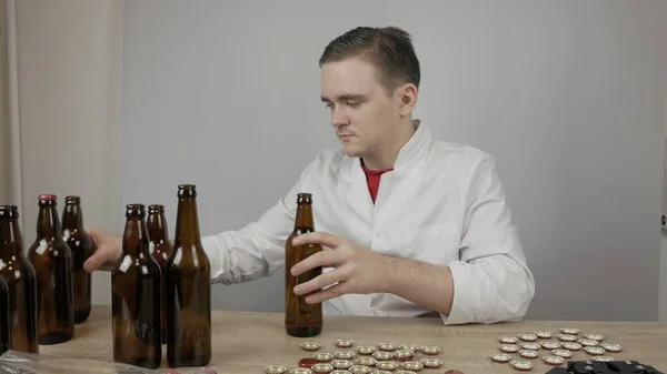 young master technologist brews beer at home, pours beer into bottles, checks the sugar level in beer, checks the percentage of alcohol in beer, checks the quality of the brewed beer