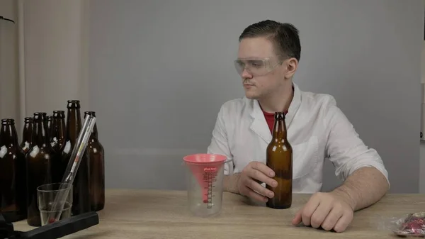 Genç bir bira üreticisi ürünleri hazırlar ve ekipmanların kalitesini ve evde demlenen ballı biranın kalitesini kontrol eder.