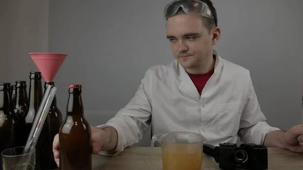 Genç bir bira üreticisi ürünleri hazırlar ve ekipmanların kalitesini ve evde demlenen ballı biranın kalitesini kontrol eder.