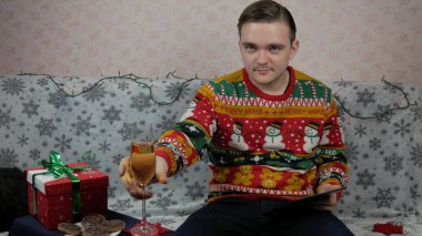 Yeni yıl tatili, genç bir adam bir hediye açar ve paketler, şampanya, yeni yıl hediyeleri, yeni yıl süslemeleri ve aile ile bir sohbet, online tablet