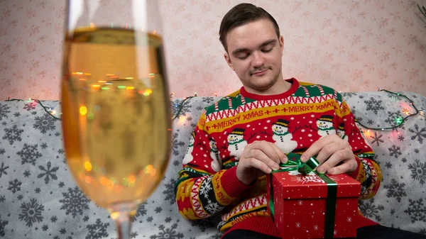 Nieuwjaarsvakantie Een Jonge Man Opent Wikkelt Een Cadeau Champagne Nieuwjaarsgeschenken — Stockfoto