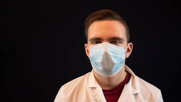 Genç doktor, beyaz önlüklü bir adam, siyah arka planda yakın plan, hastanın testlerine bakıyor.