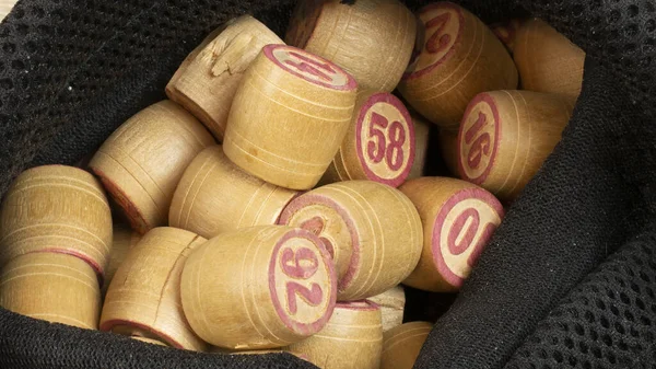 Table game Bingo. Wooden Lotto barrels, playing cards for Lotto game with black bag on a wooden light table