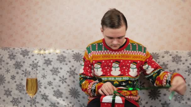 Guy New Year Sweater Sits Couch Packs Gift Red Box — Stock Video