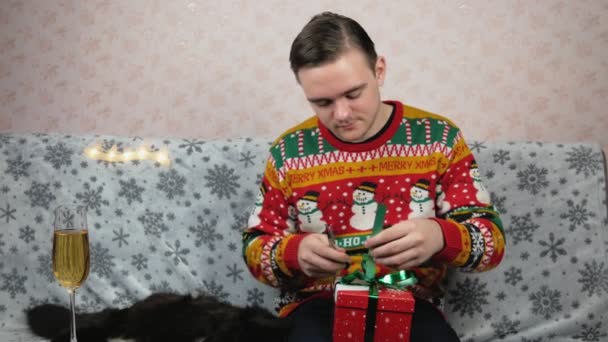 Ein Mann Neujahrspulli Sitzt Auf Der Couch Und Packt Ein — Stockvideo