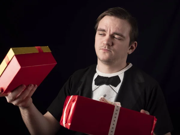 young guy in a black t-shirt suit chooses gifts on a black background