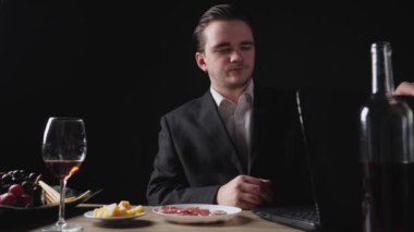 Genç bir iş adamı bilgisayarda çalışır, sonra onu kapatır, kırmızı şarabı alır ve içer. Restoran Yemeği Konsepti