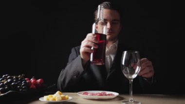 Genç bir işadamı şarap şişesinden şarap bardağına kırmızı şarap döker ve masanın üzerine koyar. Restoran Yemeği Konsepti