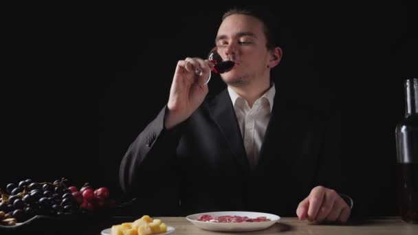 一个年轻的商人喝了一杯葡萄酒 然后吃了红葡萄 食肆晚餐概念 — 图库视频影像