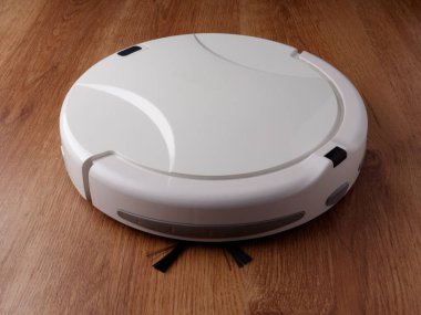 Robot elektrikli süpürge ahşap parke zeminde duruyor, ev temizliği kavramı.