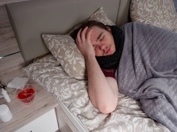 Genç adam soğuk algınlığı ilacı aldıktan sonra yatak odasında uyuyor. Hasta, evde hastalık konsepti var.