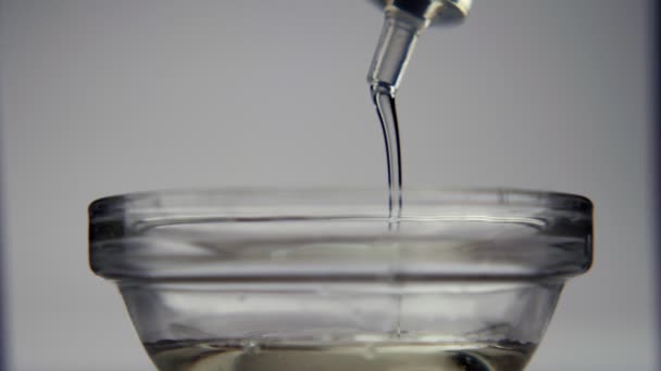 医療用注射器からガラス瓶に滴下液のクローズアップ 灰色の背景に隔離されています 医学と油の概念 — ストック動画