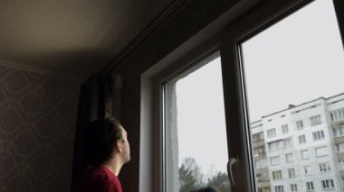 Kırmızı tişörtlü genç bir adam sarı süngerle pencereyi yıkıyor. Pencere temizleme kavramı